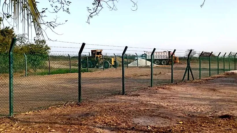 Cerramiento de lote — Malla verde con alambre de púas en patio de maquinaria — Metalworks Energy